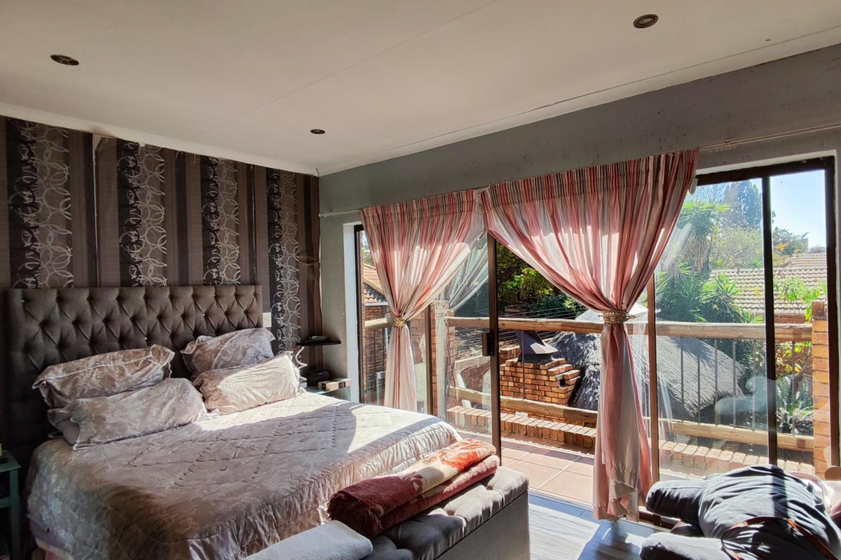 Spacious bedroom featuring laminate flooring, recessed lighting, and large sliding glass doors providing direct access to an outdoor balcony area.