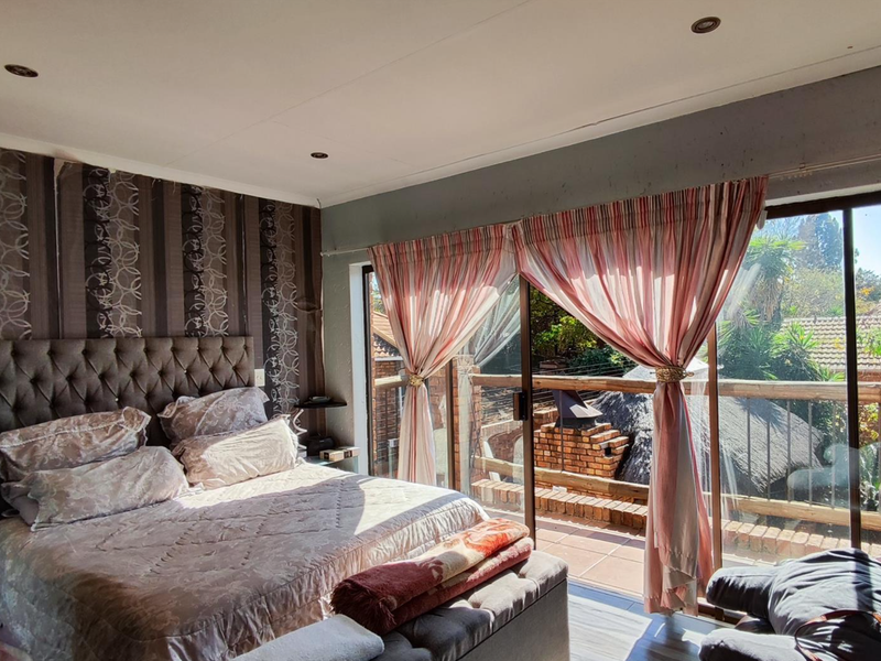 Spacious bedroom featuring laminate flooring, recessed lighting, and large sliding glass doors providing direct access to an outdoor balcony area.