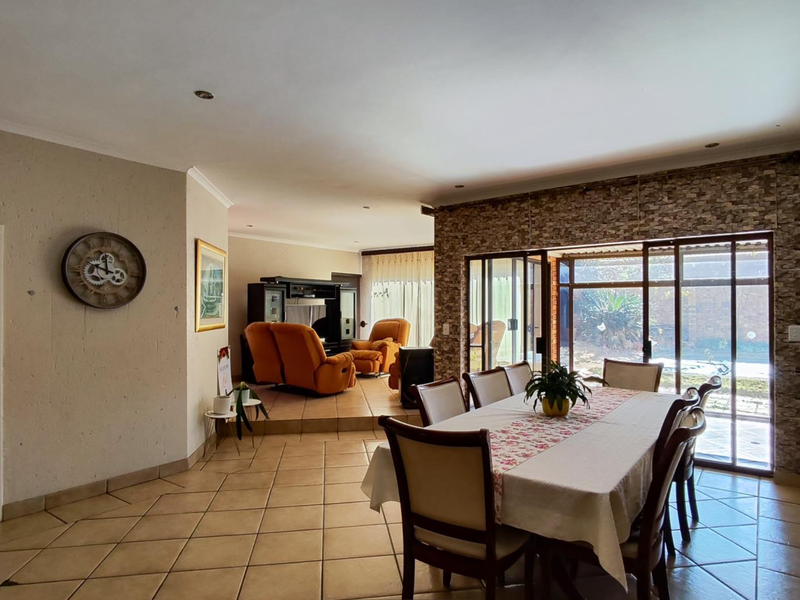 Spacious open-plan living and dining area featuring tiled floors, a stone feature wall, and large sliding glass doors providing access to the outdoor space.