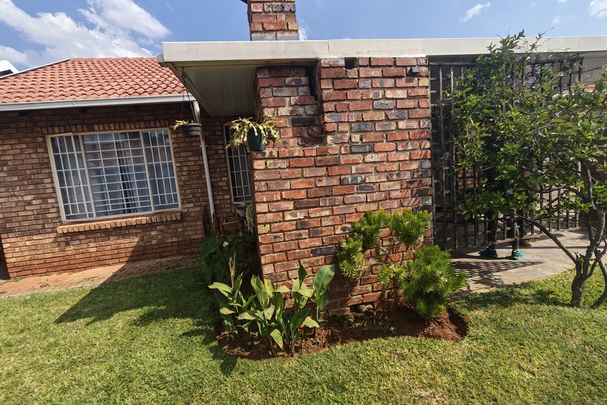 Rear exterior view of a brick townhouse featuring a tiled roof and a prominent brick chimney with visible structural cracking.