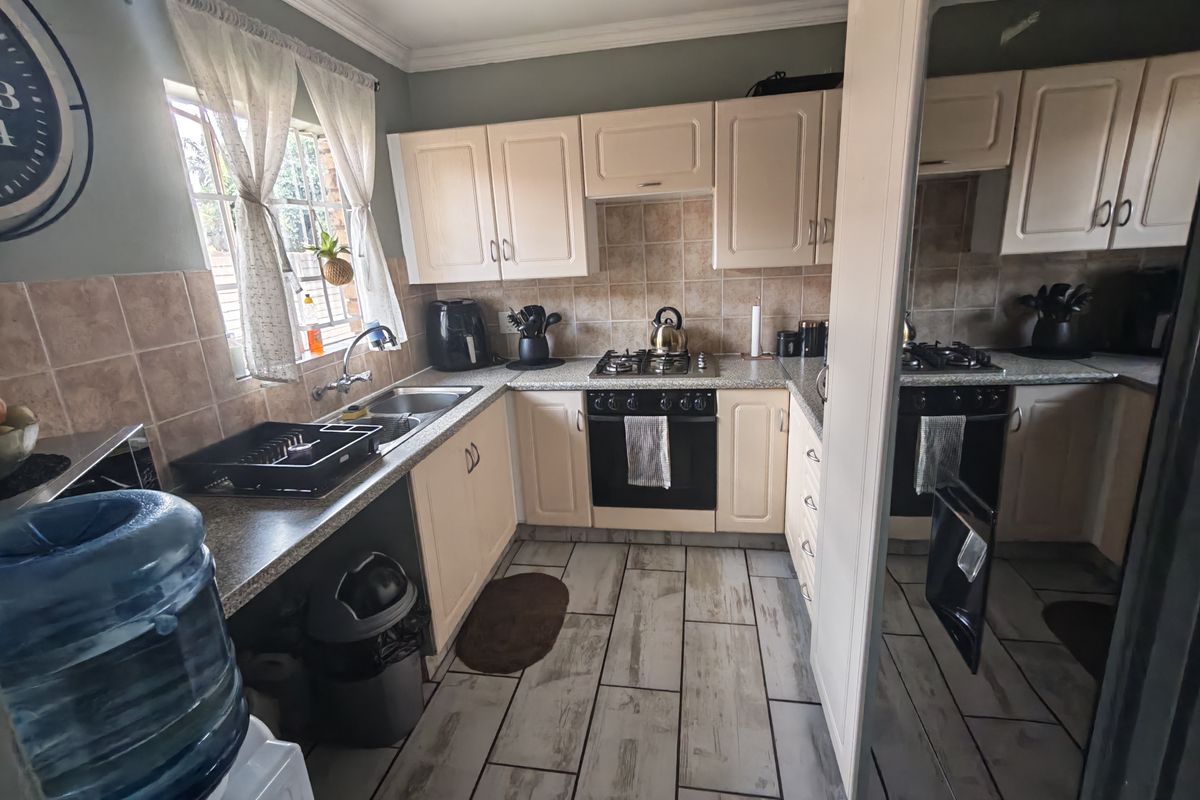 A functional kitchen featuring built-in cabinetry, a gas hob with oven, tiled backsplash, and durable tiled flooring.