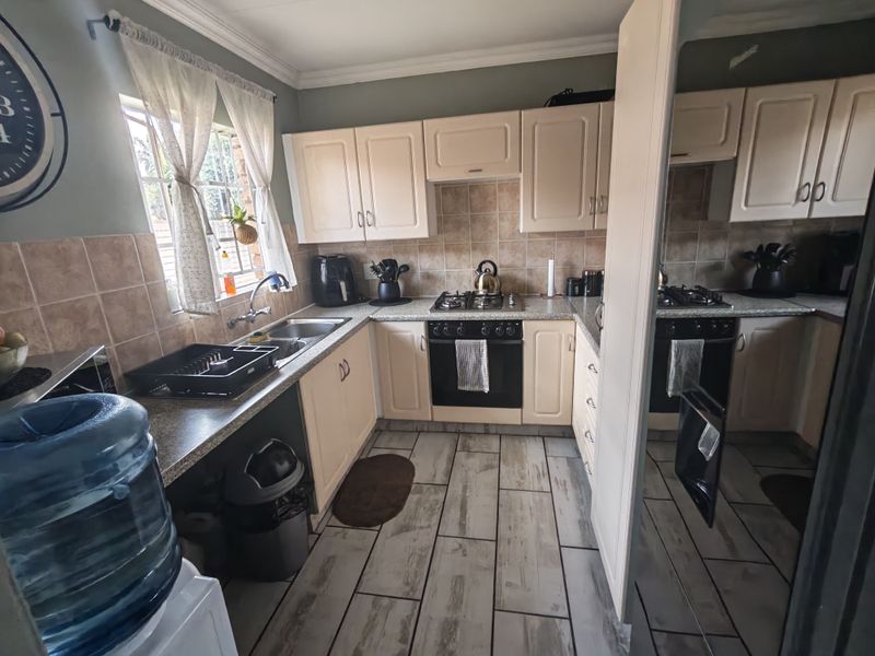A functional kitchen featuring built-in cabinetry, a gas hob with oven, tiled backsplash, and durable tiled flooring.
