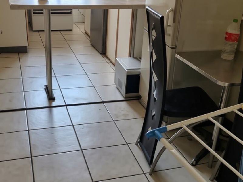 A functional kitchen featuring tiled flooring, built-in cabinetry, a breakfast bar, and a freestanding stove with security bars on the window.
