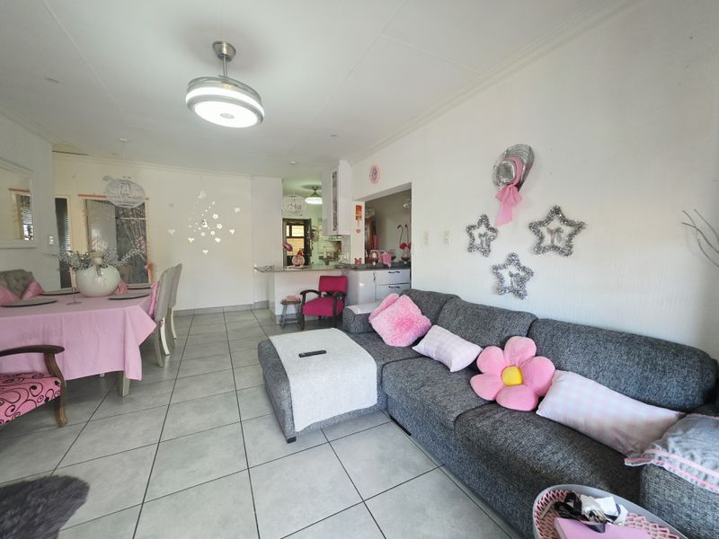 Open plan living and dining area featuring tiled flooring, a ceiling fan, and a breakfast bar connecting to the kitchen.