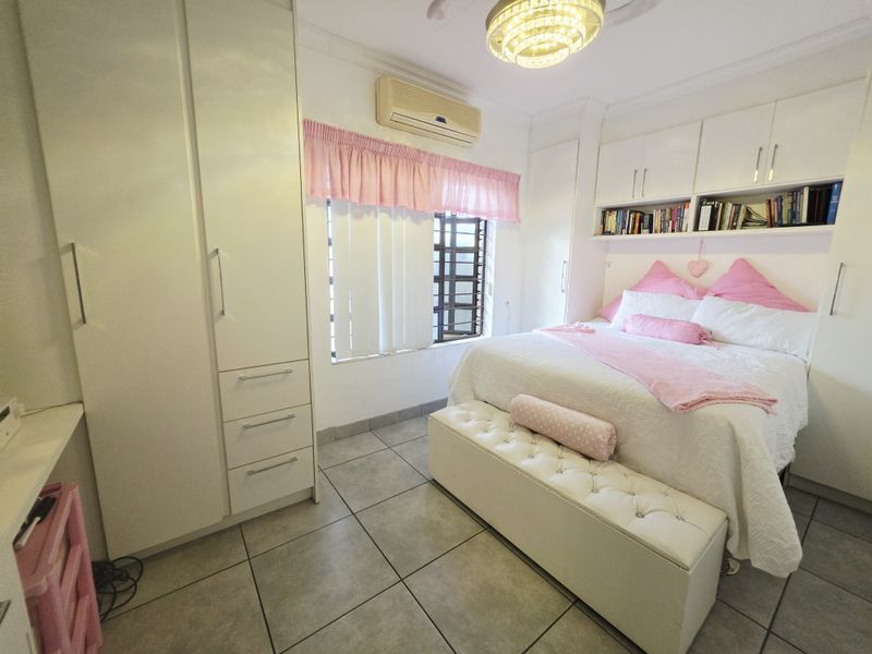 A well-maintained bedroom featuring extensive built-in cabinetry, overhead storage, tiled flooring, and an integrated air conditioning unit.