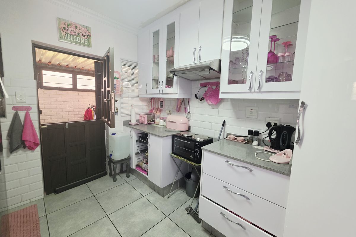 A compact kitchen featuring white cabinetry, stone countertops, subway tile backsplash, and a stable door leading to an outdoor area.