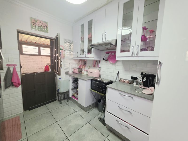 A compact kitchen featuring white cabinetry, stone countertops, subway tile backsplash, and a stable door leading to an outdoor area.