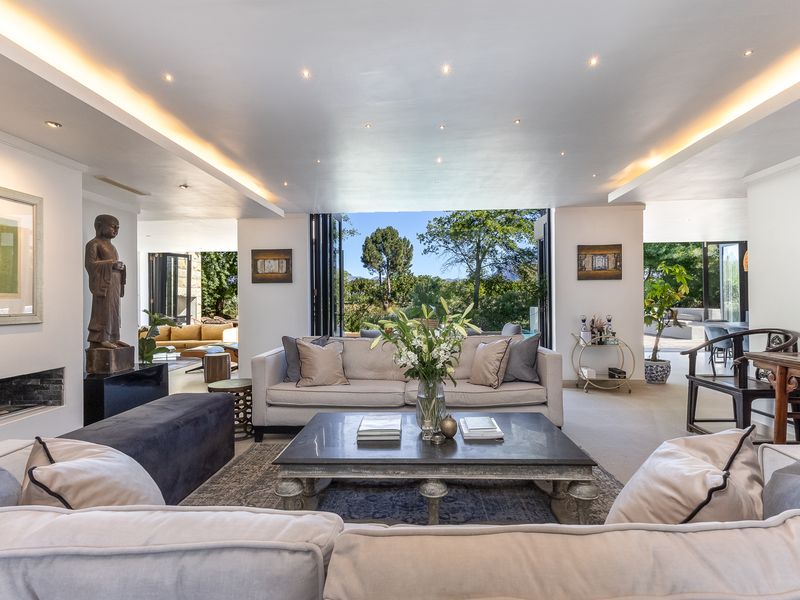 Spacious living room featuring recessed and cove lighting, a built-in fireplace, and large bi-fold doors opening to a scenic outdoor view.
