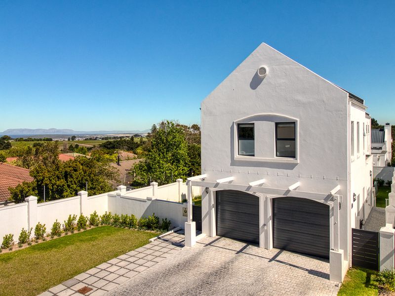 A well-maintained double-storey home featuring a double garage, paved driveway, and a pergola, set within a landscaped property with scenic views.