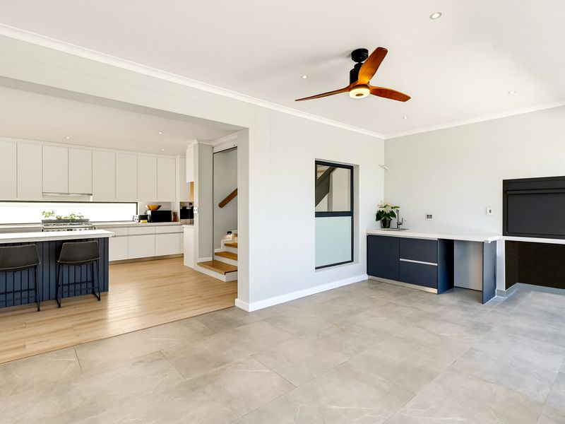 Modern open-plan living area featuring a sleek kitchen with island, integrated cabinetry, and a dedicated bar area with tiled and timber flooring.