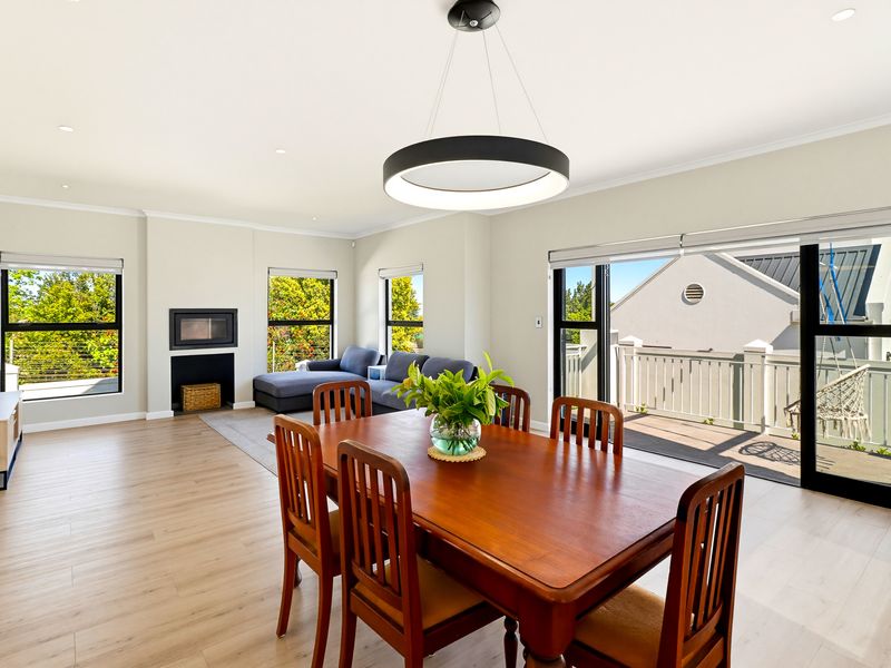 Spacious open-plan living and dining area featuring modern laminate flooring, a built-in fireplace, and large sliding doors leading to an outdoor balcony.