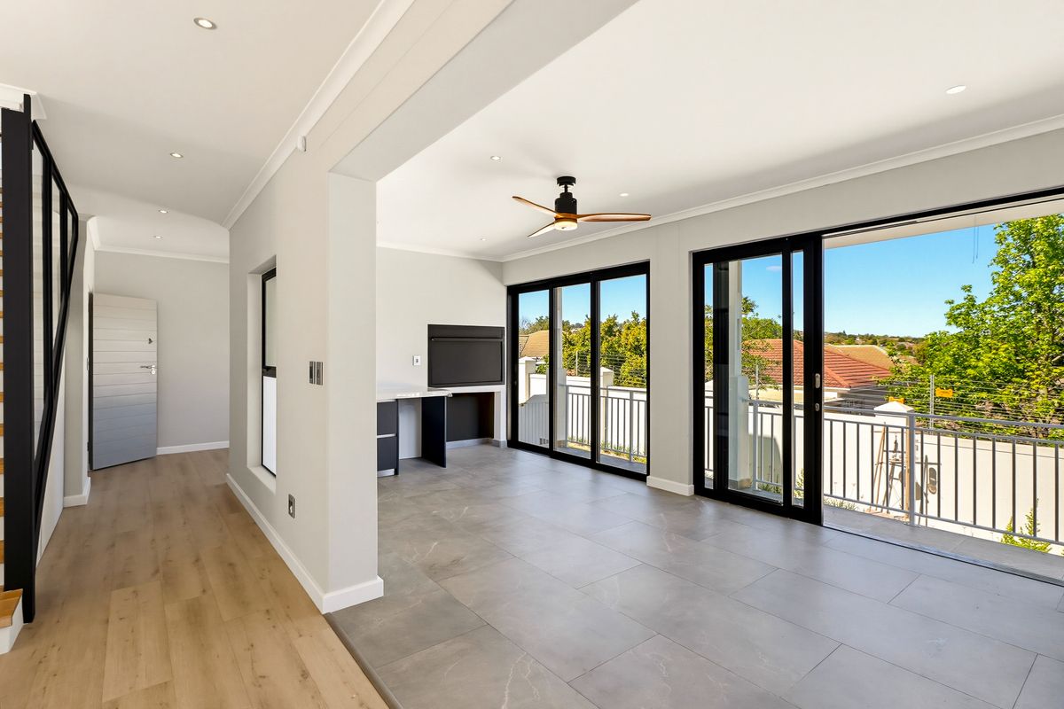 Spacious open-plan living area featuring modern tiled flooring, recessed lighting, a ceiling fan, and large sliding doors opening onto a balcony with scenic views.