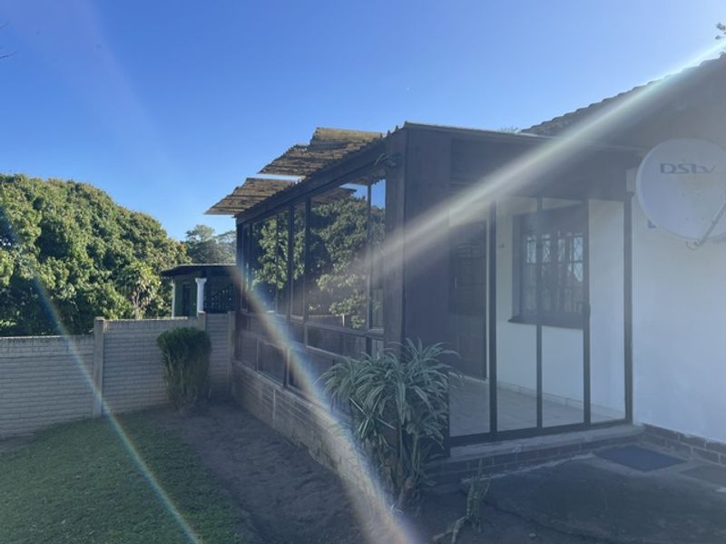 Rear view of the property featuring an enclosed patio area with aluminum frames, a tiled roof, and a surrounding boundary wall.