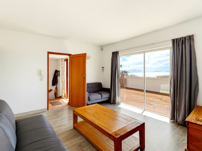 Bright living room featuring laminate flooring and a large sliding glass door providing direct access to an outdoor deck with scenic views.