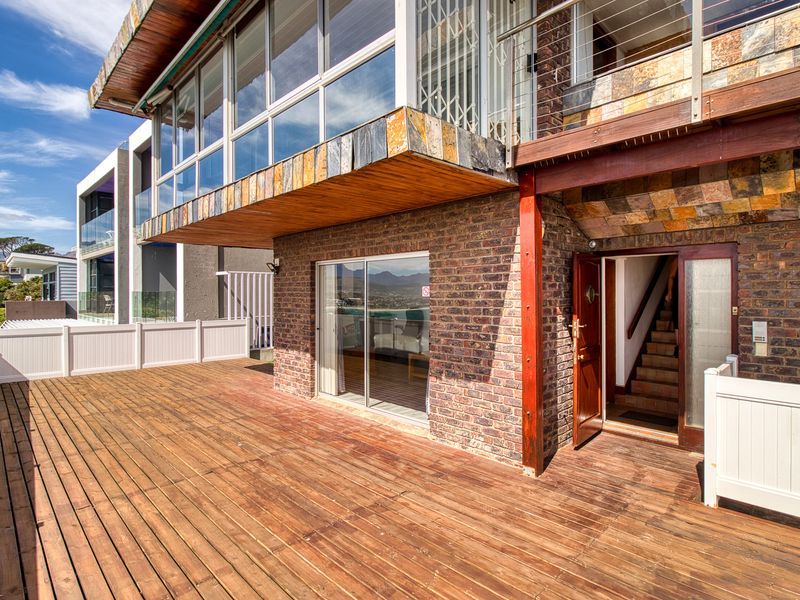 Spacious elevated timber deck featuring brick facade, stone cladding accents, and direct access to the interior via sliding glass doors and a staircase.