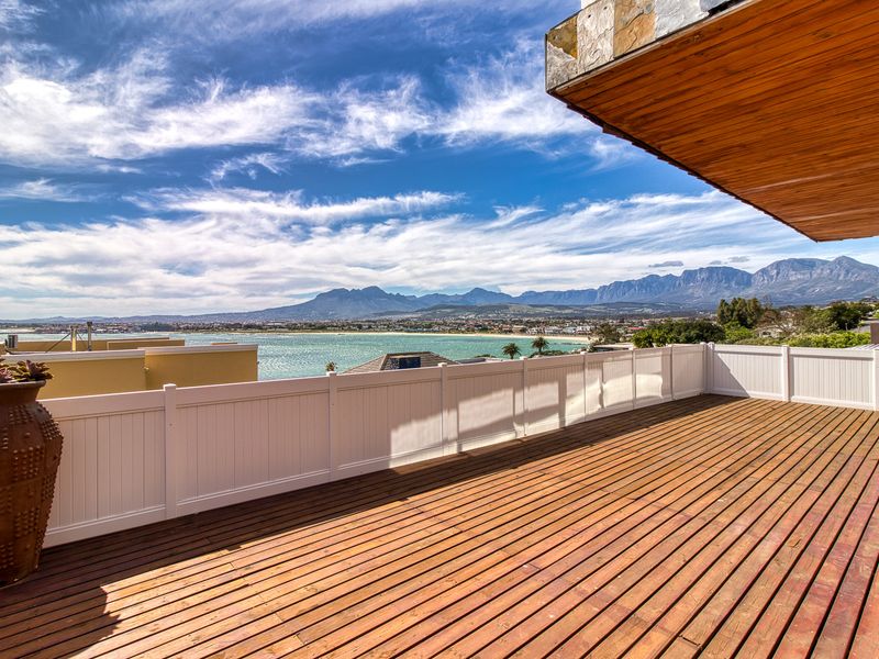 Spacious elevated timber deck featuring a vinyl balustrade and panoramic coastal and mountain views.