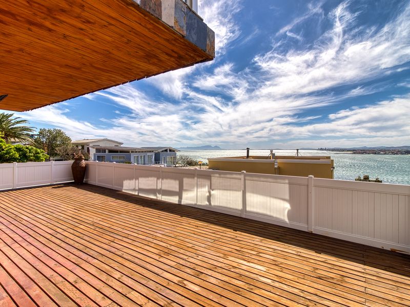 Spacious elevated timber balcony featuring a white vinyl balustrade and expansive coastal views, offering an ideal outdoor entertainment space.