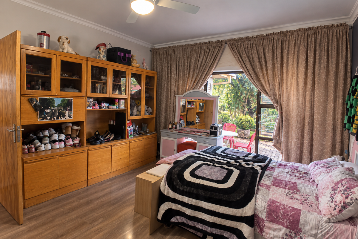 A spacious bedroom featuring laminate flooring, a ceiling fan, and extensive built-in wooden cabinetry, with direct access to an outdoor patio area.