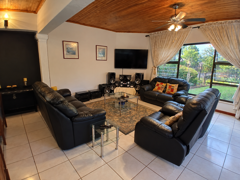 Spacious living room featuring a warm timber tongue and groove ceiling, tiled flooring, and large sliding glass doors providing access to the garden.