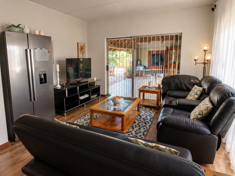 A comfortable living room featuring laminate flooring and a large sliding glass door with a security gate, providing direct access to the outdoor patio area.