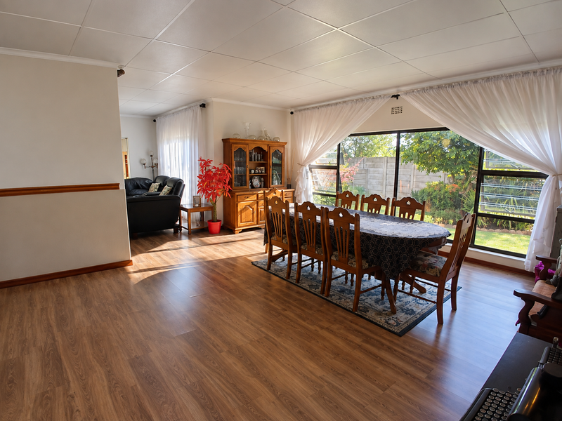 Spacious open-plan living and dining area featuring laminate flooring, large sliding glass doors providing garden access, and a neutral interior finish.