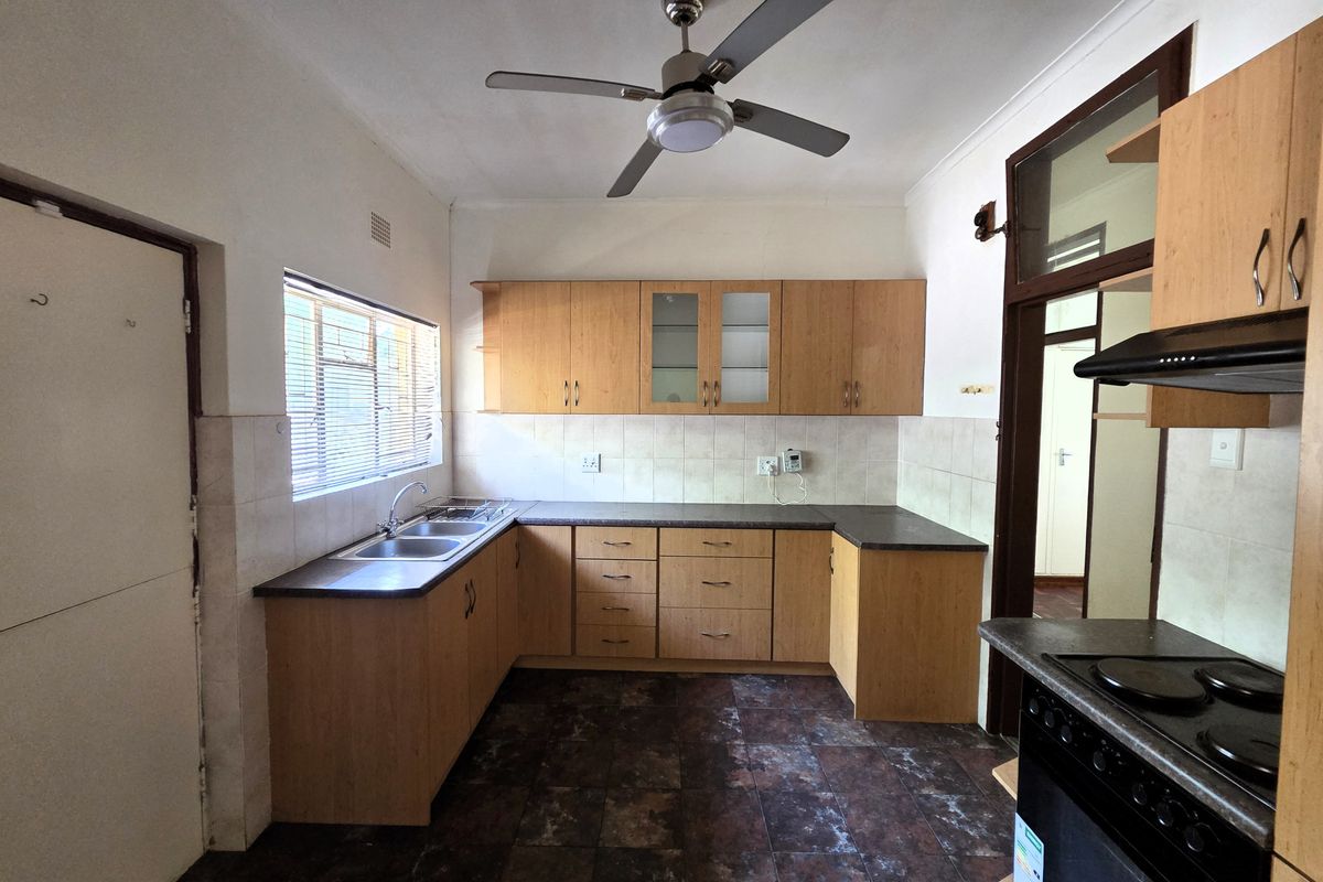 A functional kitchen featuring laminate cabinetry, a double bowl sink, built-in oven with hob, and tiled flooring, offering a practical layout for renovation.