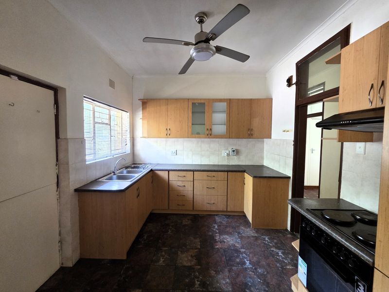 A functional kitchen featuring laminate cabinetry, a double bowl sink, built-in oven with hob, and tiled flooring, offering a practical layout for renovation.