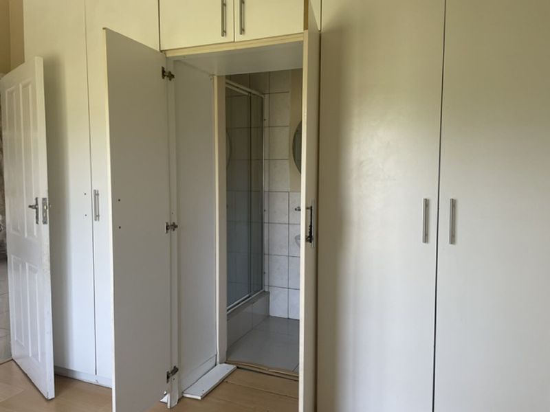 Bedroom featuring extensive built-in cupboards and direct access to an en-suite bathroom with a shower enclosure.