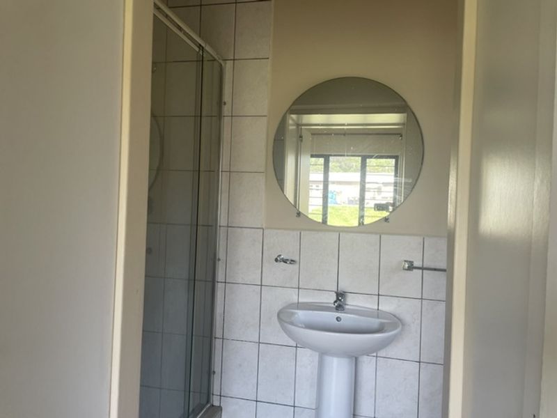 A functional bathroom featuring a pedestal basin, shower enclosure, and tiled wall finishes.
