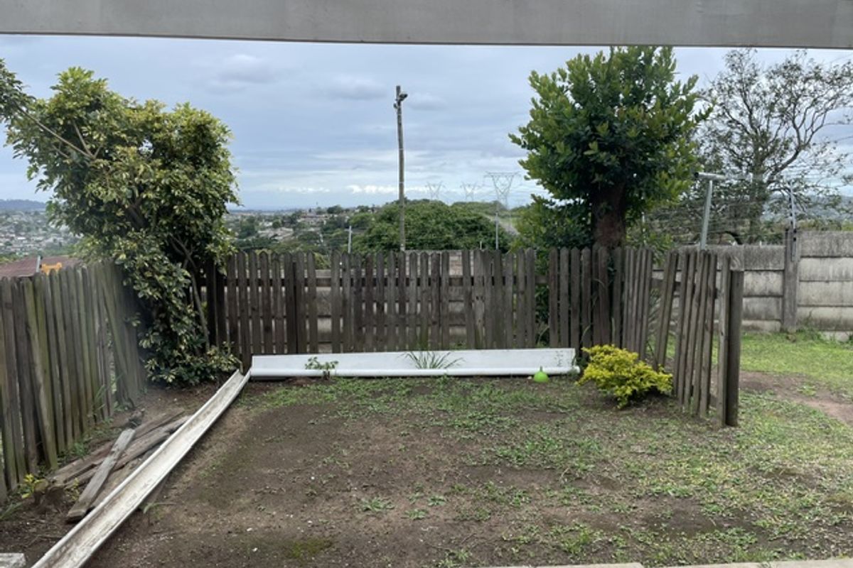 A rear outdoor area featuring a pergola structure, wooden fencing, and a paved section, currently requiring landscaping and maintenance to improve its overall condition.