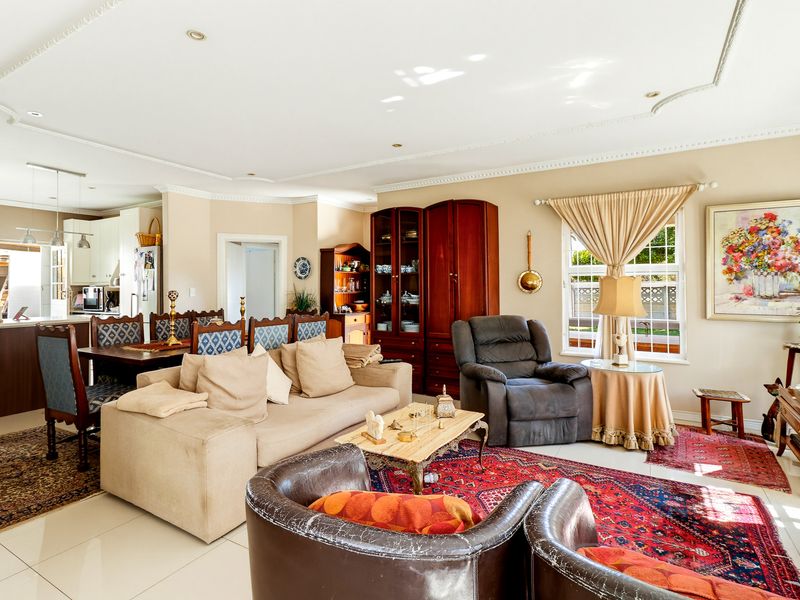 Spacious open-plan living and dining area featuring tiled floors, decorative ceiling cornices, and a seamless flow into the adjacent kitchen space.