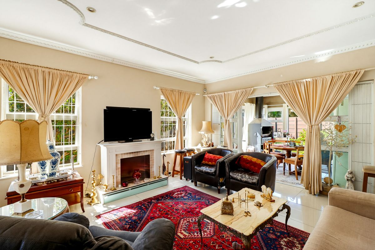 Spacious living room featuring a fireplace, decorative ceiling molding, and large windows, with seamless access to an outdoor patio area.