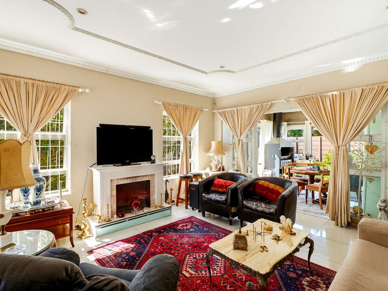 Spacious living room featuring a fireplace, decorative ceiling molding, and large windows, with seamless access to an outdoor patio area.