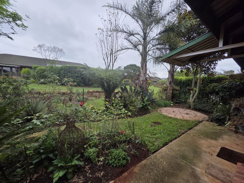 A private garden area featuring a paved patio section, established landscaping, and a covered outdoor space, offering a peaceful retreat within the retirement village.