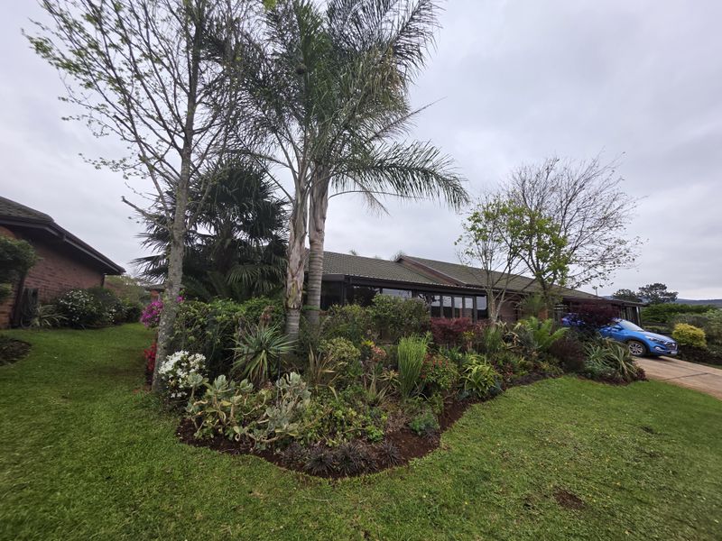 Front view of a retirement village residence featuring a well-maintained landscaped garden, brick exterior, and tiled roof with a paved driveway.