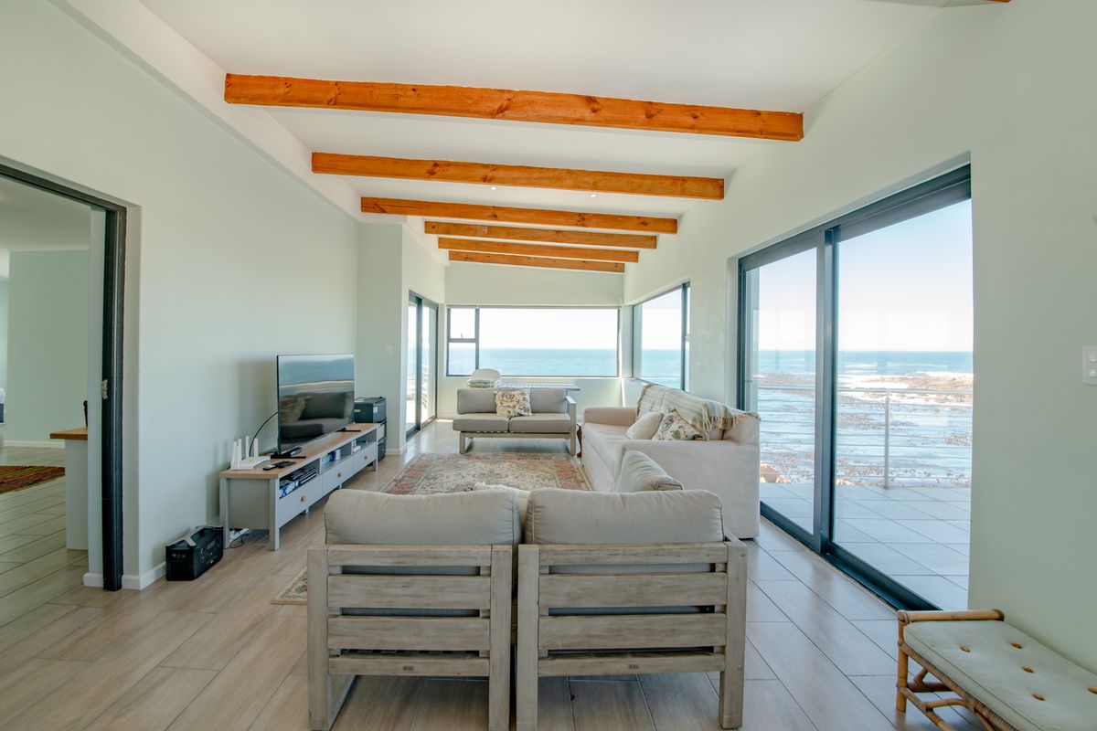 Bright and airy living room featuring exposed timber ceiling beams, large sliding glass doors, and expansive ocean views.
