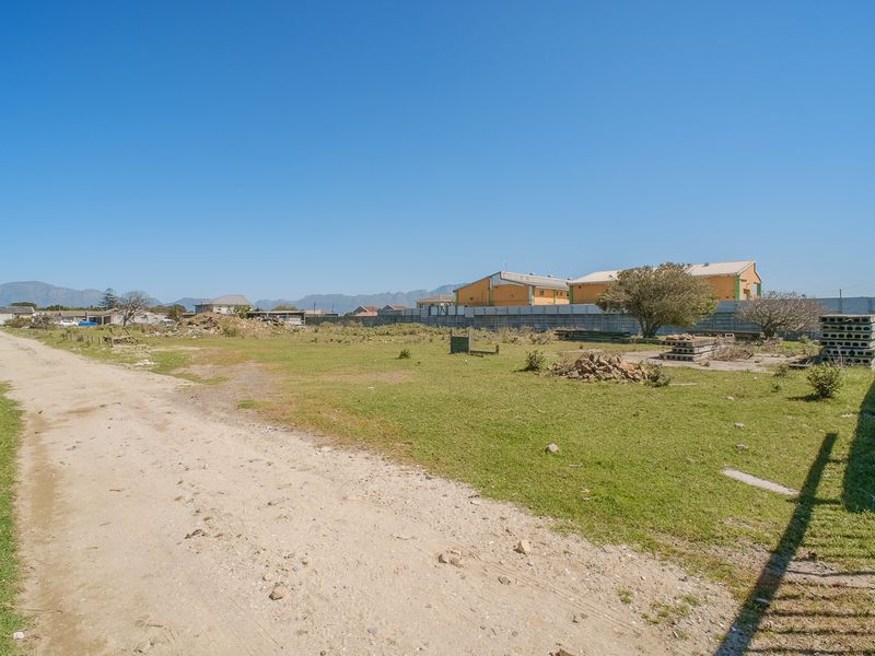 A vacant plot of land featuring an unpaved driveway, perimeter walling, and open grass area, suitable for future development.