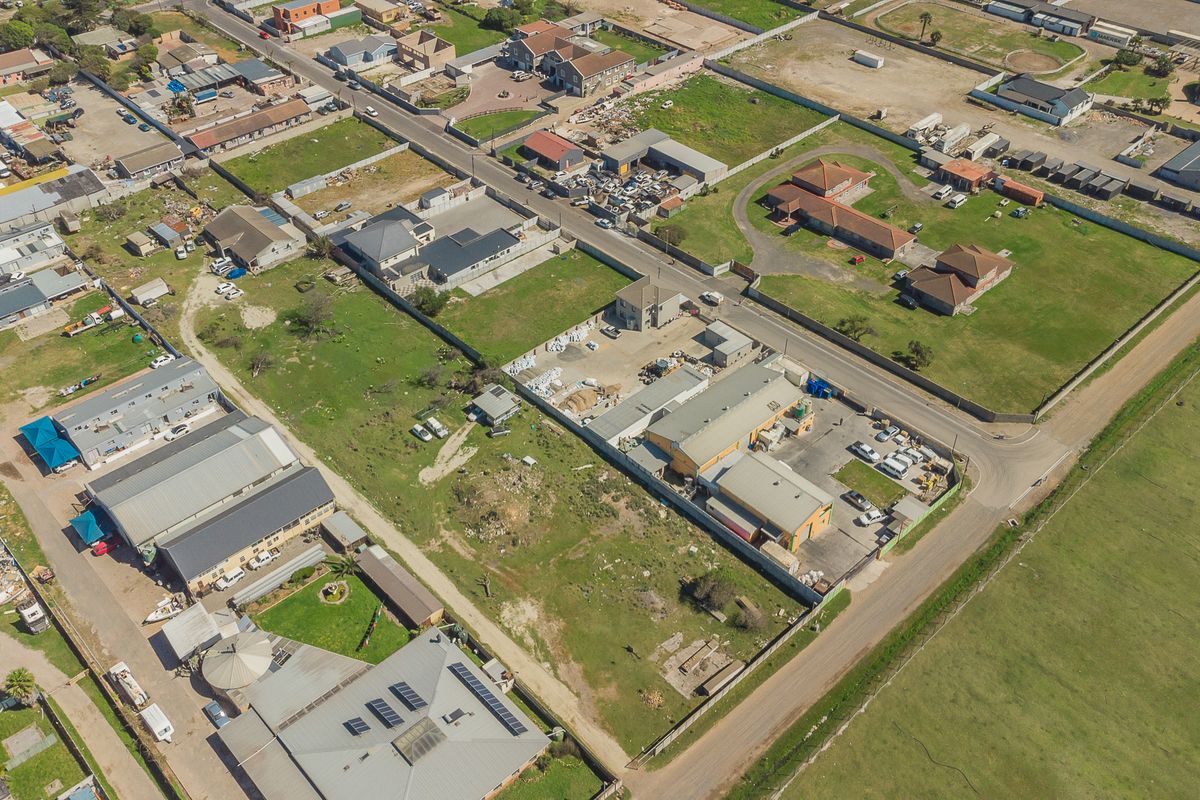 An aerial view of the property and surrounding neighborhood, showcasing the building layout, roof structure, and site access.