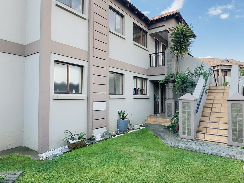 Exterior view of a multi-story apartment building featuring a tiled staircase, glass block accents, and a landscaped front garden area.