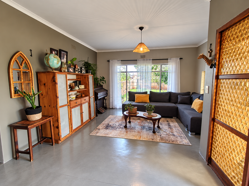A bright and spacious living room featuring polished concrete floors, a decorative textured glass partition, and large sliding doors providing natural light and garden access.