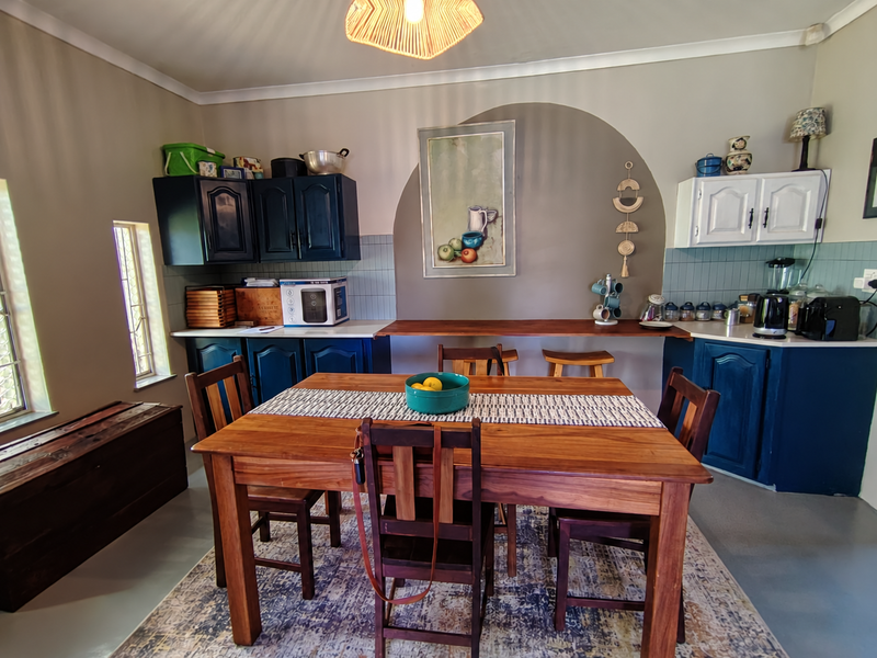 Open plan kitchen and dining area featuring dark blue and white cabinetry, tiled backsplash, and a built-in breakfast bar.