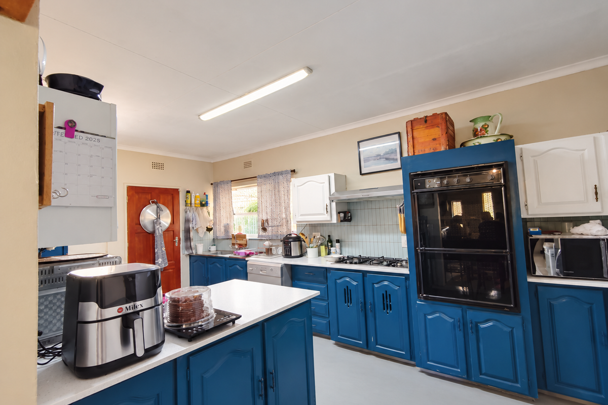 A functional kitchen featuring blue cabinetry, a built-in oven, gas hob, extractor fan, and a central island with ample counter space.