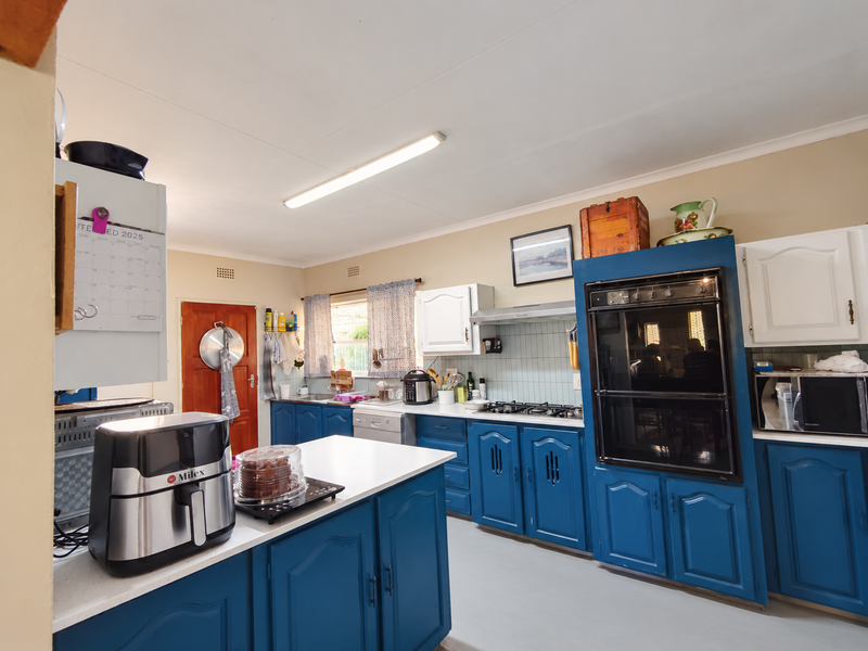 A functional kitchen featuring blue cabinetry, a built-in oven, gas hob, extractor fan, and a central island with ample counter space.