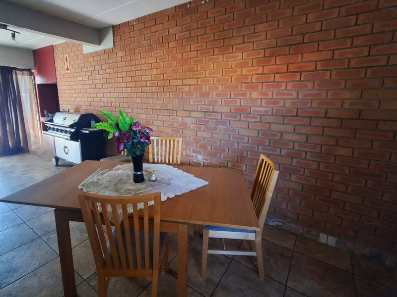 Dining area featuring a prominent exposed brick feature wall and durable tiled flooring, creating a rustic and functional space.