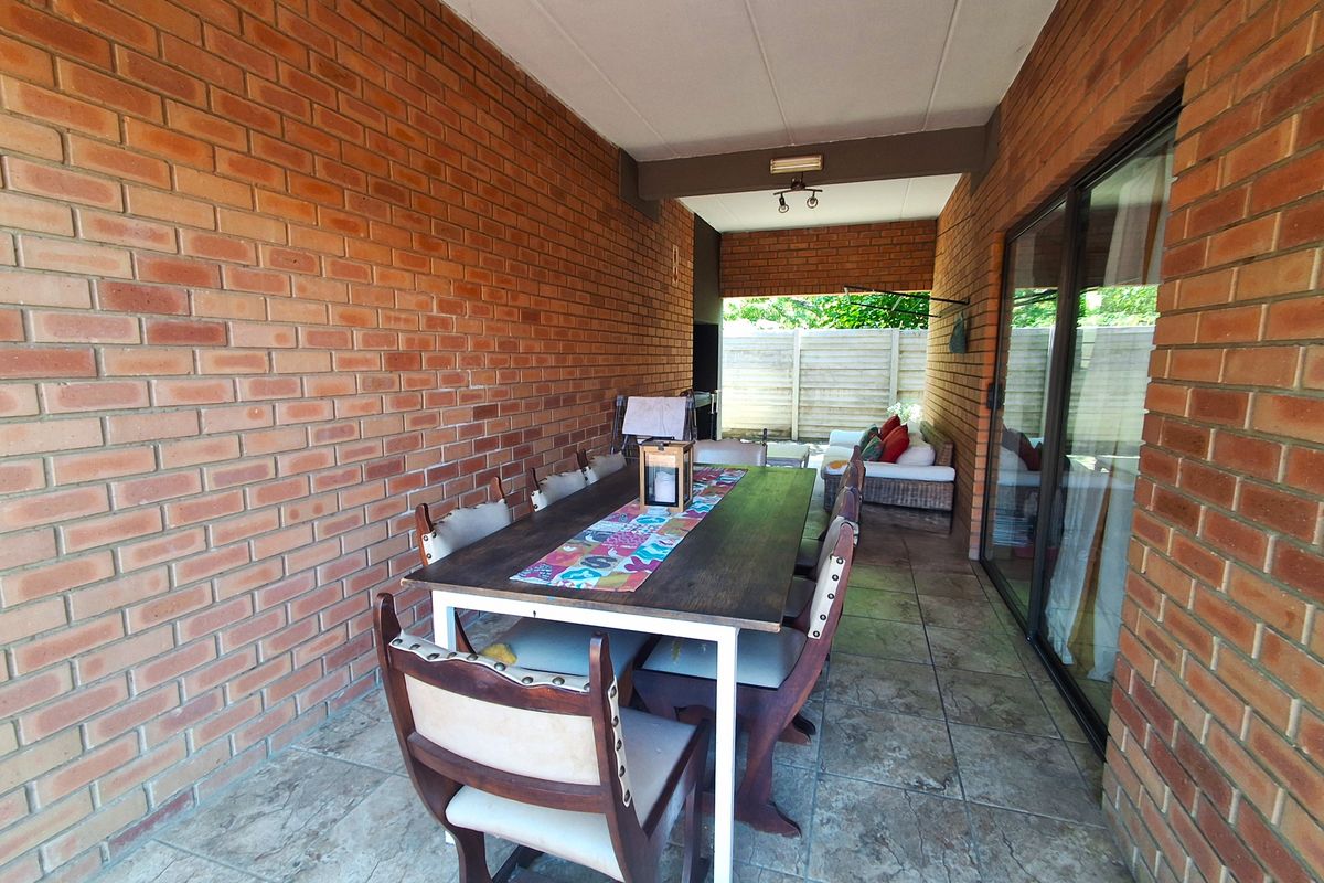 A covered patio area featuring exposed brick walls, tiled flooring, and sliding glass doors providing access to the interior living space.