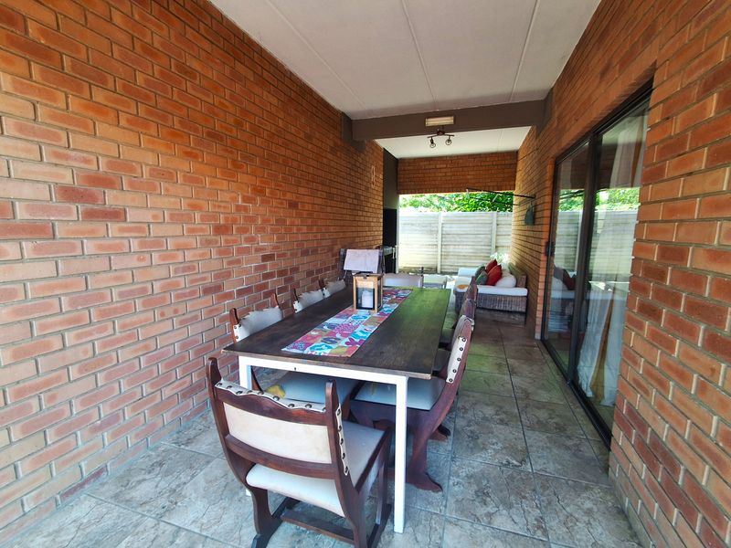 A covered patio area featuring exposed brick walls, tiled flooring, and sliding glass doors providing access to the interior living space.