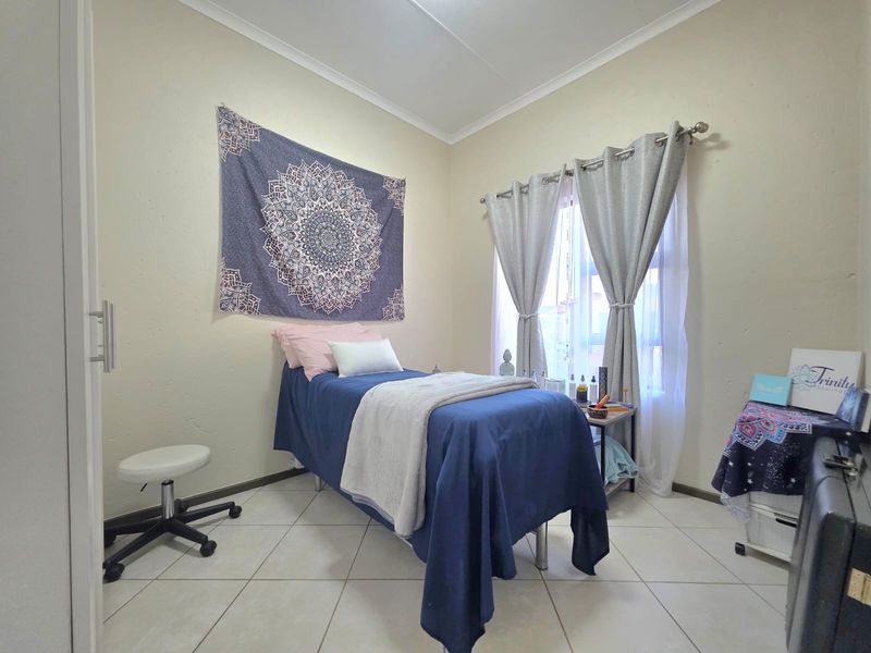 A functional bedroom featuring tiled flooring and a built-in cupboard, currently utilized as a treatment room.