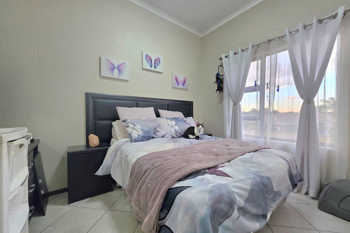 A well-lit bedroom featuring tiled flooring and a large window with curtain fixtures, providing a comfortable and functional living space.