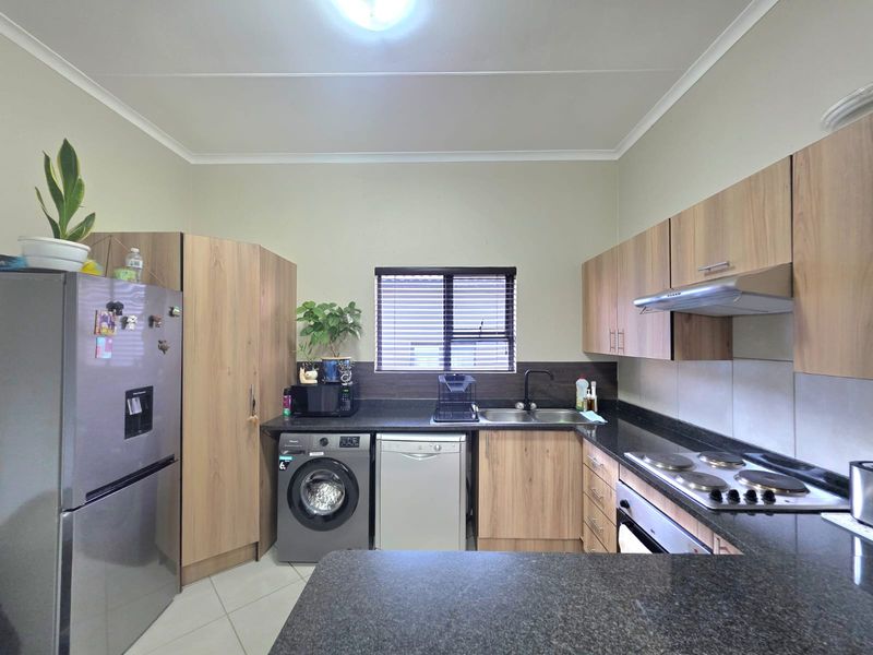 A functional kitchen featuring wood-look cabinetry, granite countertops, a built-in oven with hob, and an integrated extractor fan.