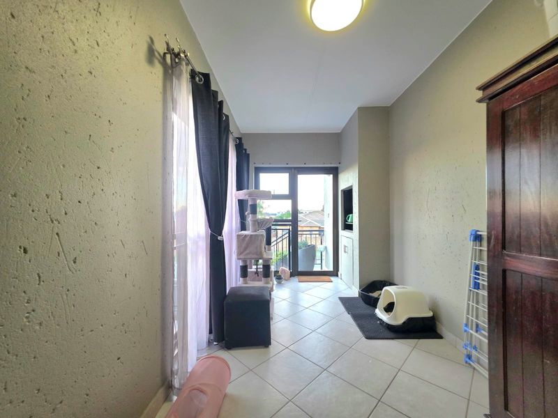A functional living area featuring tiled flooring, built-in shelving, and a sliding glass door providing access to an outdoor space.